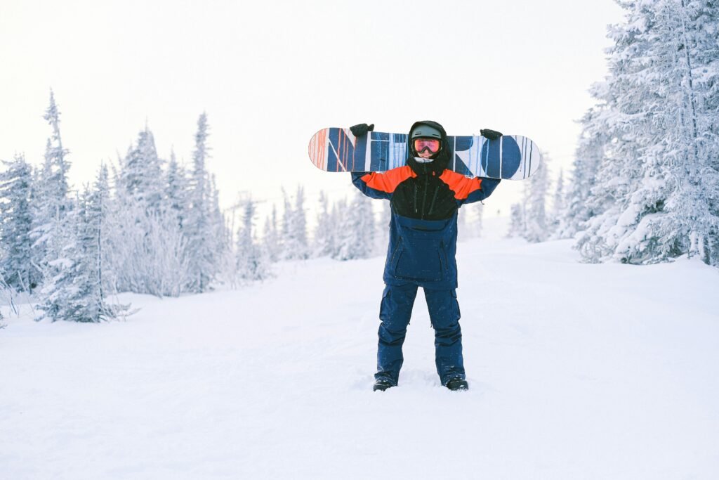 Snowboarder with arms raised on a snowy landscape, showcasing winter sports excitement.